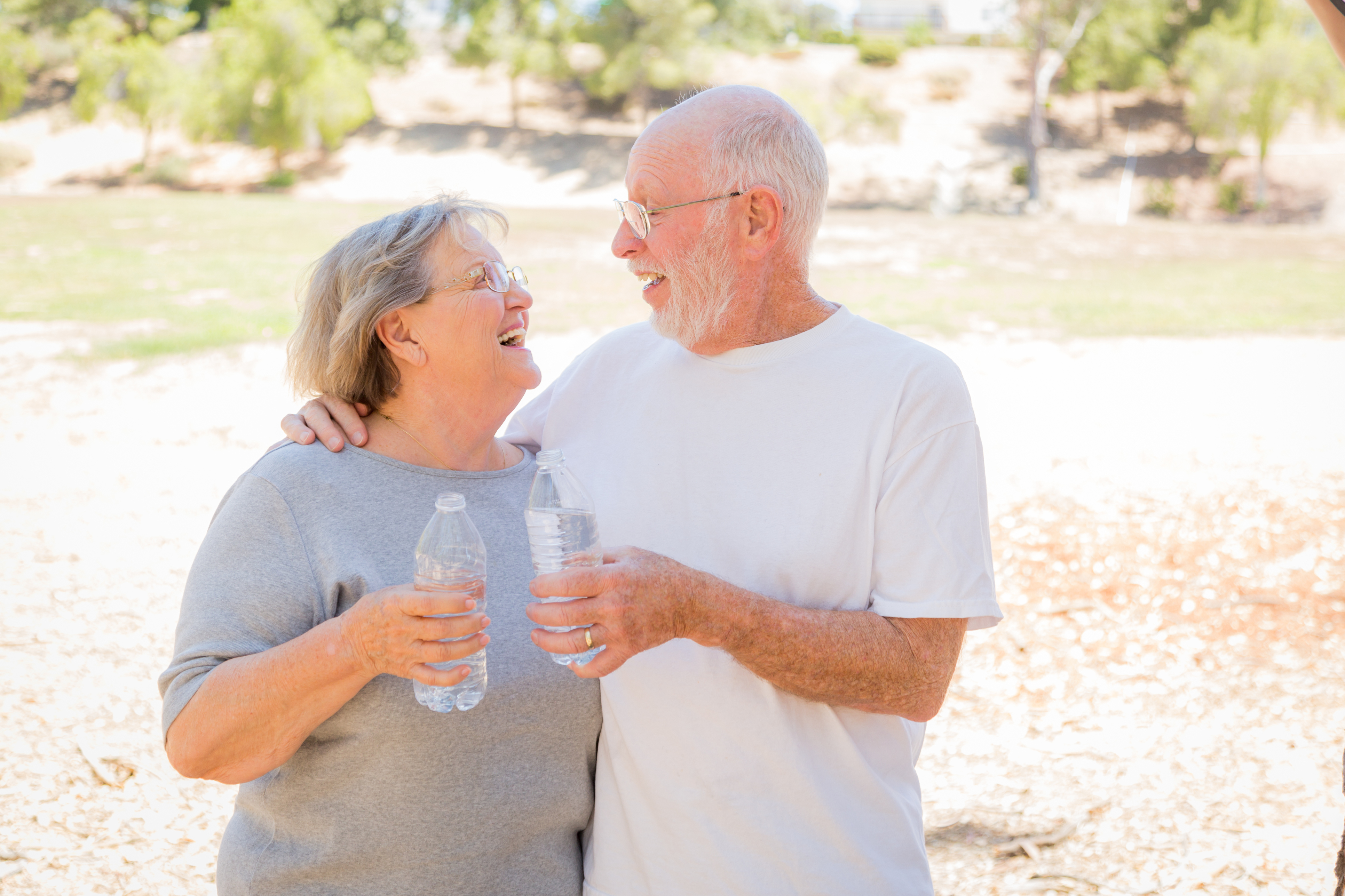 A senior couple staying hydrated in the summer, with their water bottles in-hand. Senior hydration is important to keep in mind during the summer months.