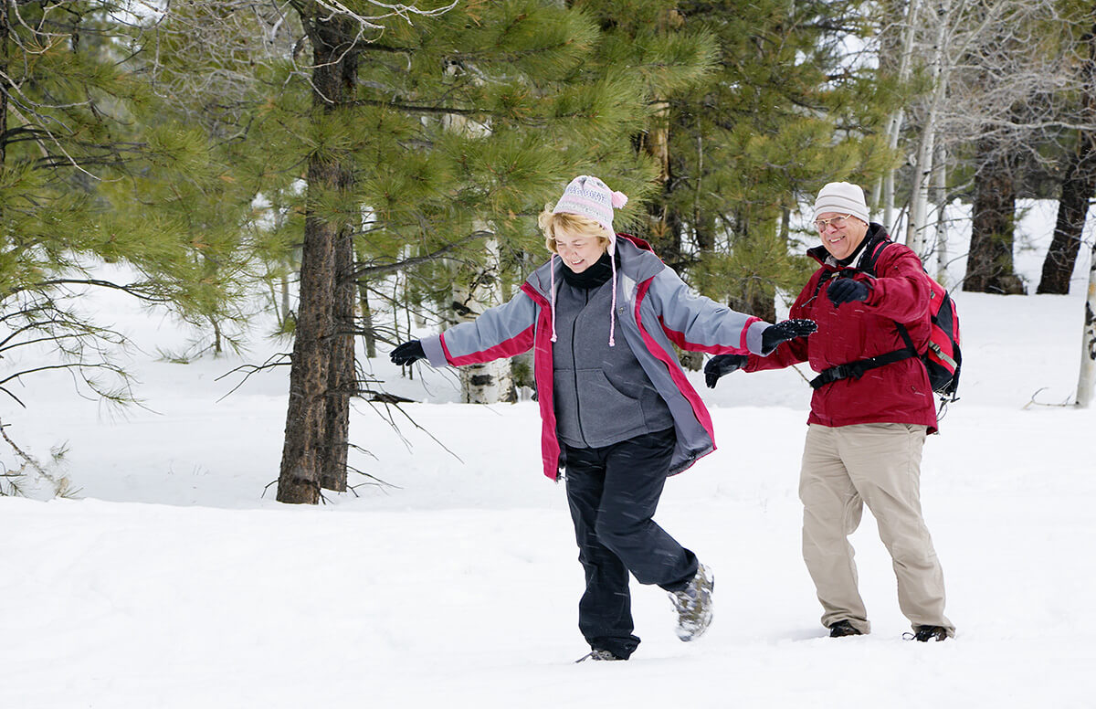 A senior couple takes a relaxing stroll in the snow. Taking time for yourself will help you avoid holiday stress.