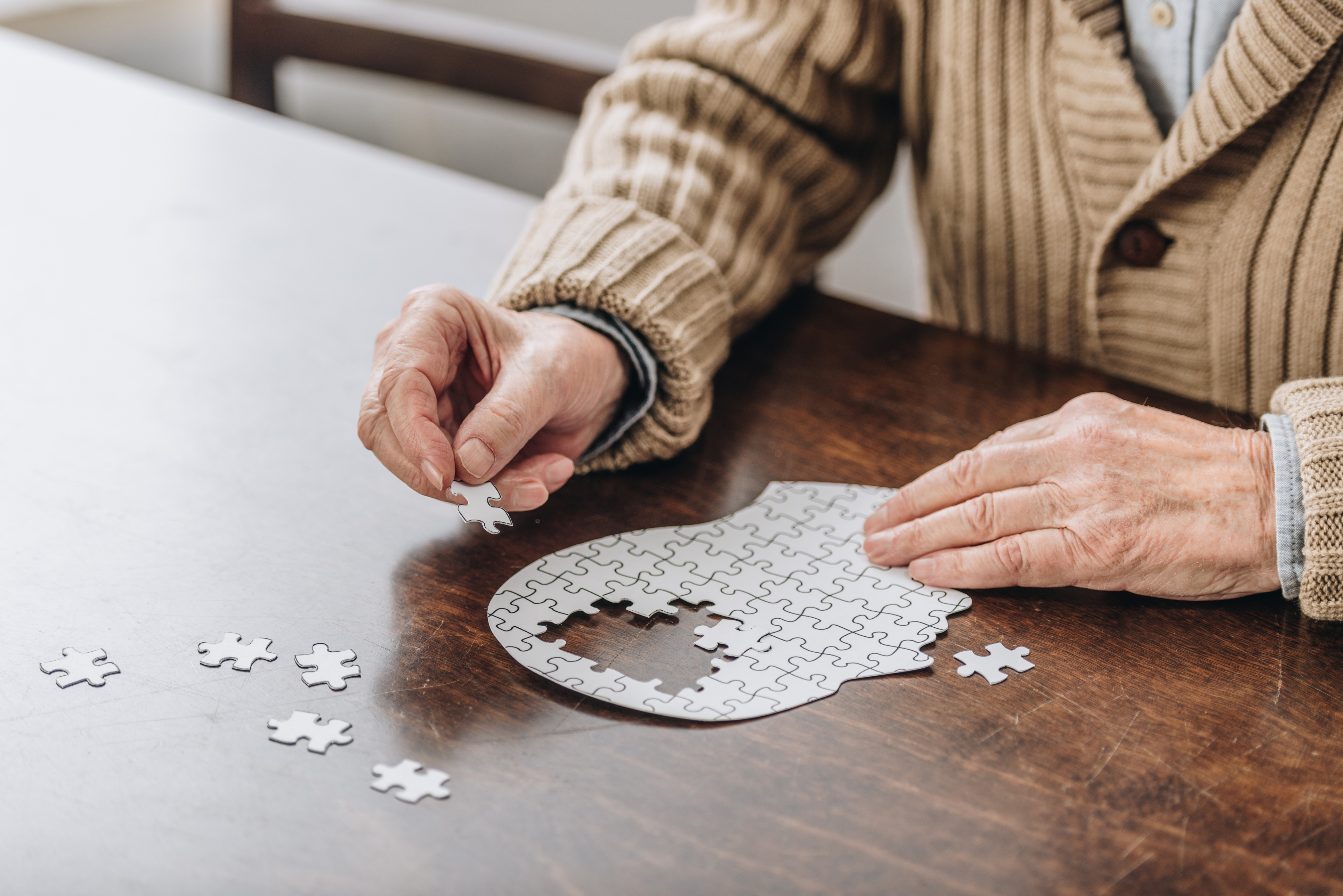 A senior man works on a puzzle, as he knows the importance of brain health