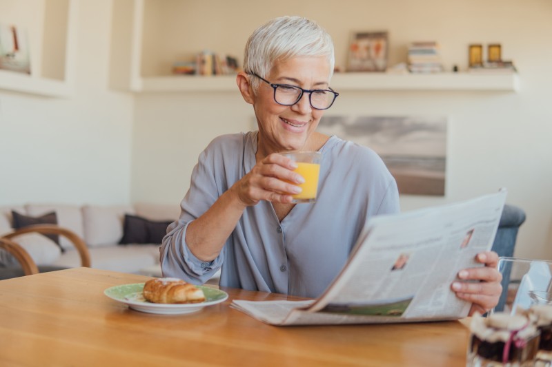 A senior woman enjoys the paper in her home, while she's aging in place.